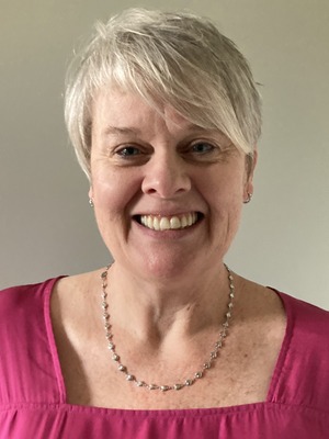 professor wearing a pink shirt in front of a tan backdrop